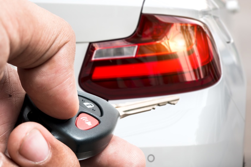 man’s hand pushing button on key fob