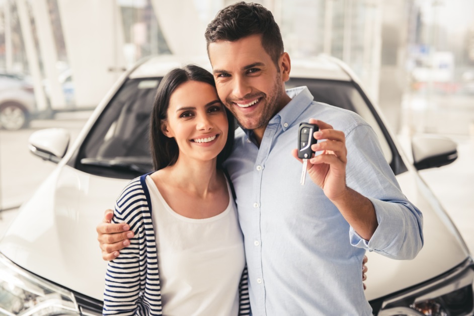 couple posing in front of their car