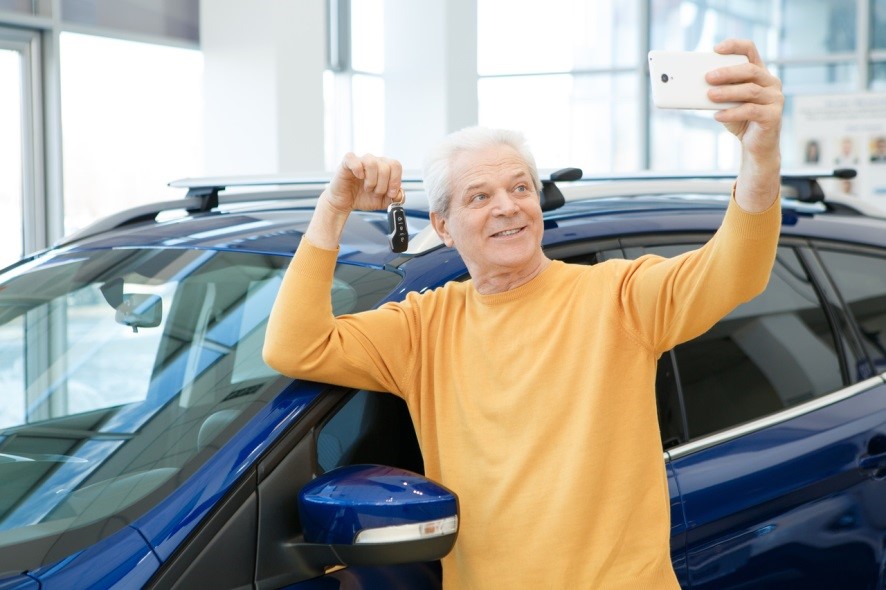 senior man posing with new car